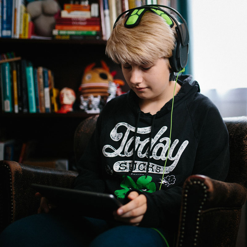 A teen wearing headset connecting to tablet which helps them interact with the Neurofeedback application.